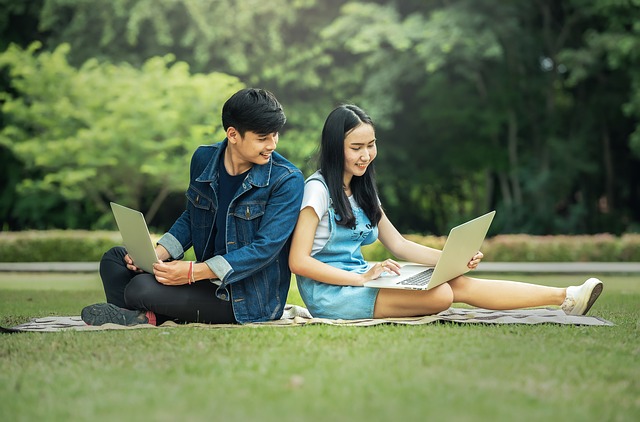 boy,girl students, online learning on the lawn