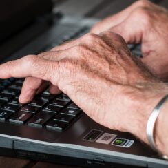 elderly hands typing on a computer keyboard