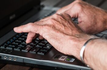 elderly hands typing on a computer keyboard